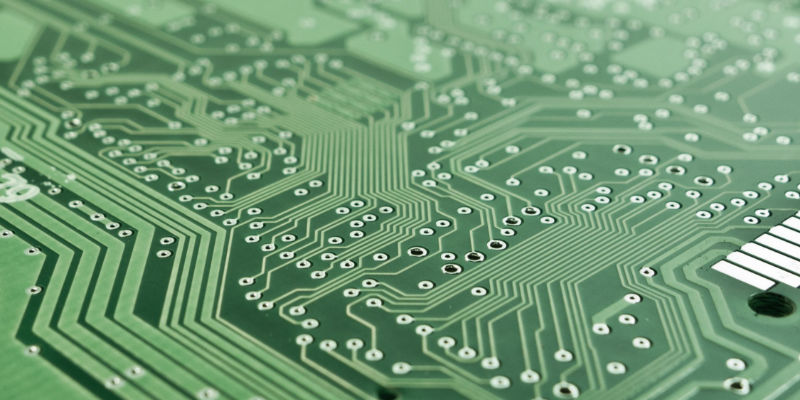 Close-up of a green printed circuit board showing copper traces and solder pads